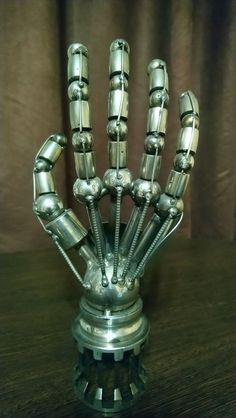 a metal sculpture that looks like a hand made out of nuts and bolts on a wooden table