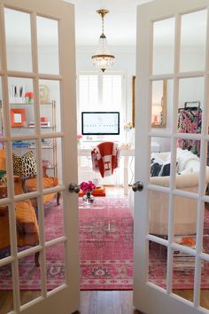 an open door leading to a living room with pink rugs on the floor and white walls