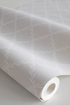 a white wallpaper with leaves and vines on the side, next to a roll of paper