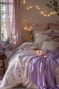 a bed covered in purple sheets and pillows next to a window with fairy lights on it