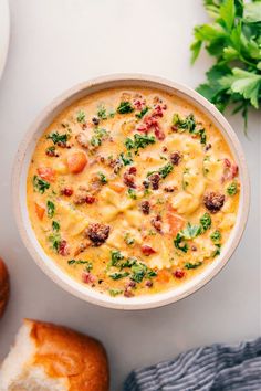 a white bowl filled with soup next to bread and parsley sprigs on the side