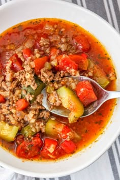 a white bowl filled with meat and vegetable soup on top of a striped table cloth