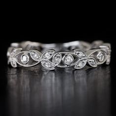 a white gold wedding ring with diamonds on it's sides and leaves in the middle