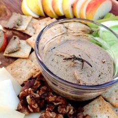 a plate with crackers, apples and walnuts next to a bowl of dip