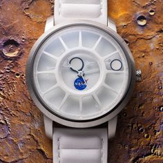 a close up of a wrist watch on a surface with paint splattered in the background