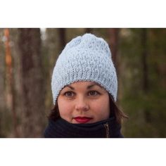 a woman wearing a blue knitted hat and scarf in the woods looking at the camera