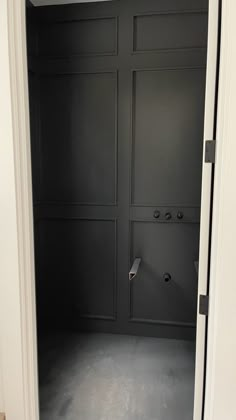 an empty room with black painted walls and white trim on the door, is seen in this image