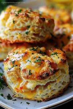 three cheesy biscuits on a plate with lemons and parsley in the background