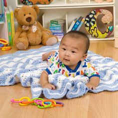 a baby sitting on the floor with toys in front of him and looking at the camera