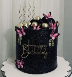 a black and gold birthday cake with pink flowers