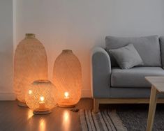 two vases sitting next to each other on a wooden floor in front of a couch