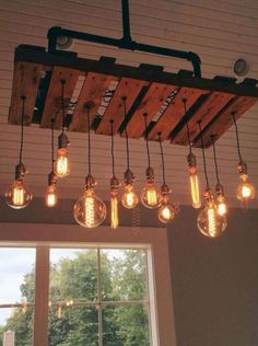 an overhead light fixture made out of wood and hanging from the ceiling above a window