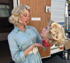 two women are eating food out of their mouths while standing in front of a trailer