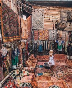 a child sitting on top of a rug in a room filled with lots of carpets