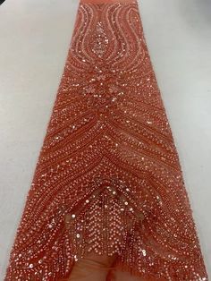 an orange dress with sequins is being held up by someone's hand