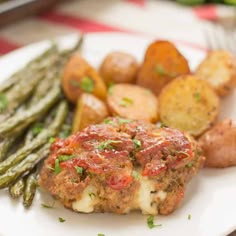 a white plate topped with meat patties, potatoes and asparagus