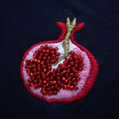 an embroidered pomegranate on a black shirt with red beads and sequins