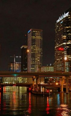 the city is lit up at night with lights reflecting in the water