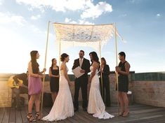 a group of people standing next to each other on a wooden floor under a white canopy