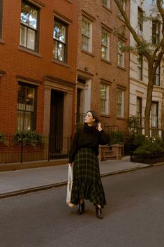 a woman is walking down the street with her hand on her head and looking up