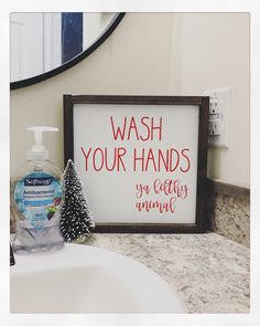 a bathroom sink with a sign that says wash your hands and a christmas tree next to it