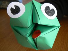 an origami frog made out of paper with eyes and nose on it's head