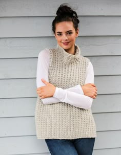 a woman standing with her arms crossed wearing a sweater vest