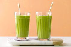 two glasses filled with green smoothie and straws