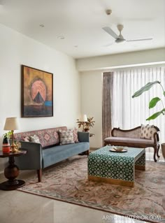 a living room filled with furniture and a painting on the wall above it's windows