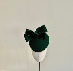 A truly elegant dark green fascinator with bow detail. This beautiful percher style hat has been made from wool felt in a rich shade of deep bottle green. Simple in style, it features a double bow - one in matching wool felt, and the other in stunning dark green velvet. This headpiece measures 20cm front to back and 17cm side to side. It is fitted with a fine elastic in a colour to blend in with your own hair colour that sits to the back of the head and underneath the hairline and would be total Green Fascinator Hat, Luxury Green Mini Hats For Races, Luxury Green Fascinator For Races, Luxury Green Wedding Hats And Headpieces, Luxury Curved Brim Green Headpiece, Green Evening Hat, Green Curved Brim Fascinator For Evening, Green Formal Hat Headpiece, Green Curved Brim Headpiece For Evening