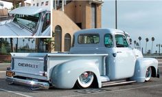 an old blue truck parked in a parking lot next to a building and palm trees