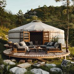 a yurt in the woods with couches and chairs on it's deck