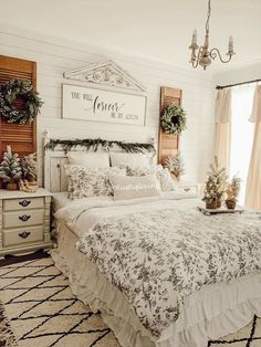 a white bed sitting in a bedroom next to a window and a chandelier