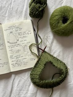 two balls of yarn next to an open notebook