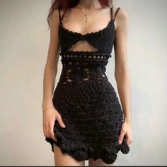 a woman with red hair wearing a black crochet dress and holding her hands on her hips