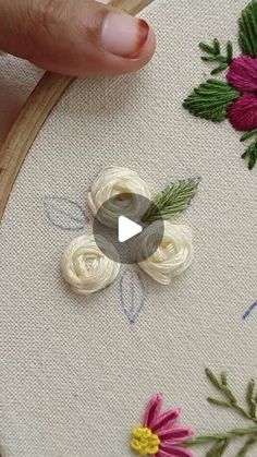 someone is stitching flowers on a piece of fabric