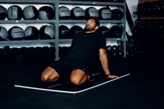 a man sitting on top of a mat in a gym