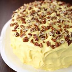 a cake that is sitting on top of a white plate with pecans around it