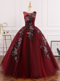 Ushering in a new era of prom sophistication, could this gown be the key to unlocking a night of elegance? Unmatched in grandeur, the dress's one-shoulder bodice is a marvel of embroidery, with flowers that seem to spring to life against the rich burgundy background. The skirt, in its majestic fullness, is a symphony of tulle and texture, graced with the same floral embroidery that adorns the bodice. A waistband cinches the dress, creating a silhouette that is both regal and flattering. This dress is the embodiment of a modern fairytale, ready to make your prom night legendary. Quinceanera Dresses Coral, Burgundy Ball Gown, Gold Sequin Shorts, Burgundy Background, Tulle Balls, Blue Ball Gowns, Liquid Satin, Modern Fairytale, Lace Ball Gowns