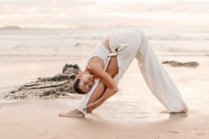 a woman is doing yoga on the beach