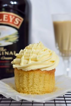 a cupcake on a plate next to a bottle of booze