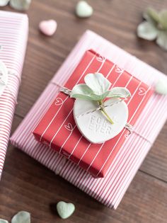 two wrapped gift boxes sitting on top of a wooden table next to flowers and petals