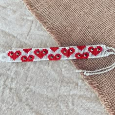 a red and white ribbon with hearts on it sitting on a piece of burlock