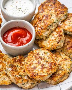 crab cakes on a plate with ketchup and dipping sauce