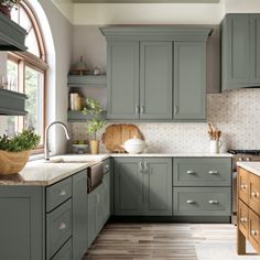 a kitchen filled with lots of green cabinets and counter top space next to a window