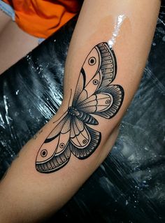 a black and white butterfly tattoo on the arm