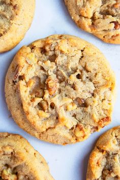 several cookies with nuts and crumbles sitting on top of a white countertop