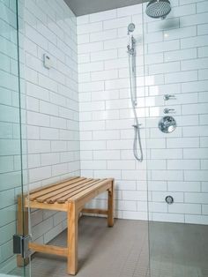 a wooden bench sitting in the middle of a bathroom next to a walk in shower