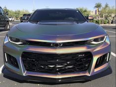 the front end of a silver camo car in a parking lot with other vehicles