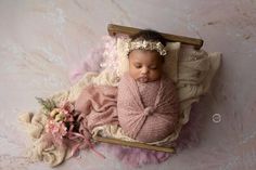 a newborn baby is sleeping in a wooden crate with pink and white flowers on it